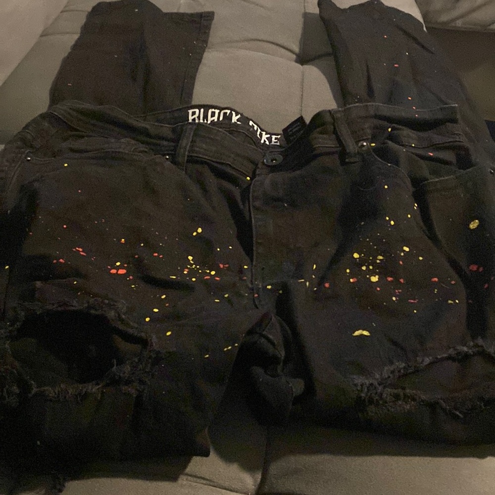 Black distress jeans yellow and red paint splashes all the way down the legs